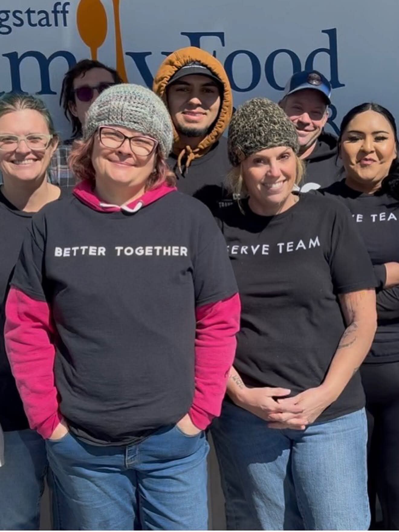 Flagstaff Dream Center serve team standing together in front of the Flagstaff Family Food Bank sign